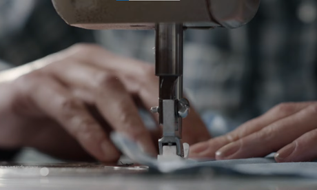 A close of a piece of fabric getting stitched by a sewing machine